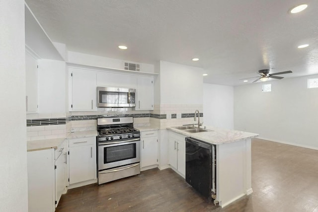 kitchen featuring visible vents, a peninsula, a sink, stainless steel appliances, and dark wood-type flooring