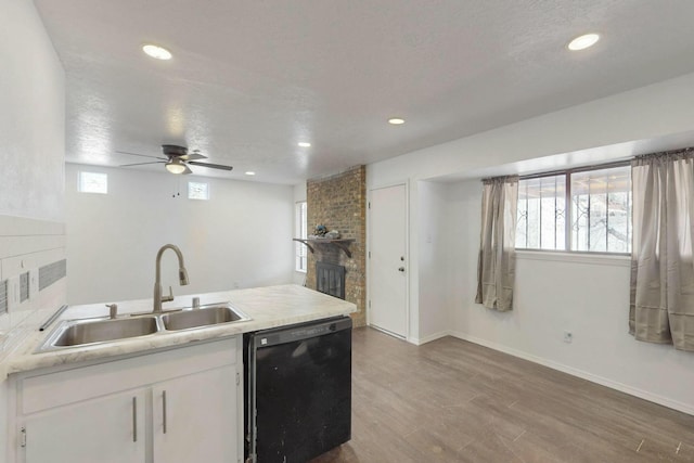 kitchen featuring a sink, black dishwasher, a wealth of natural light, and white cabinetry