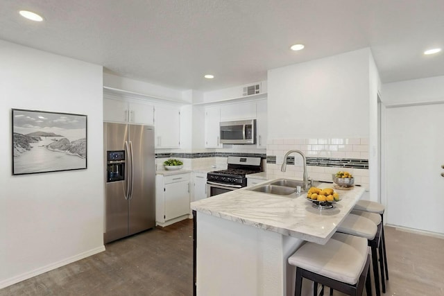 kitchen with visible vents, a peninsula, a sink, stainless steel appliances, and backsplash