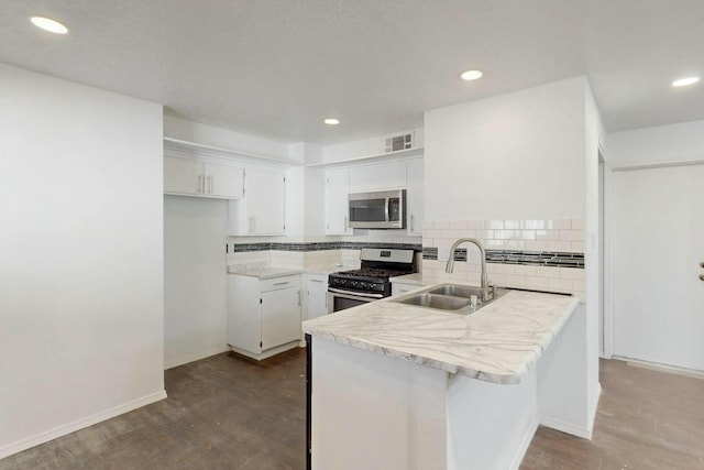 kitchen featuring visible vents, a sink, backsplash, stainless steel appliances, and a peninsula