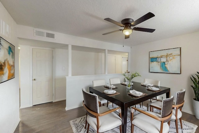 dining room featuring visible vents, a ceiling fan, a textured ceiling, wood finished floors, and baseboards