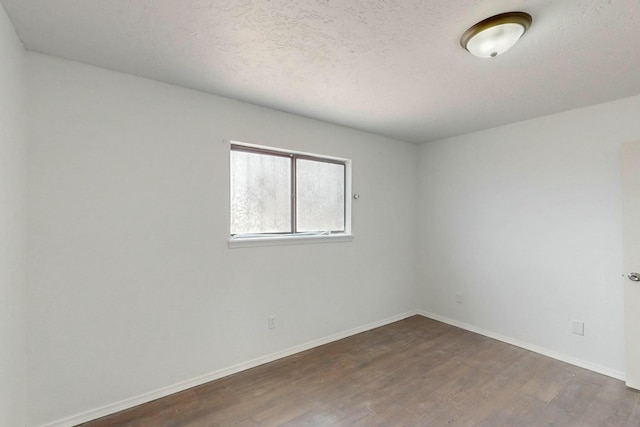 empty room with a textured ceiling, baseboards, and dark wood-style flooring