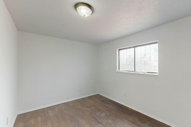 unfurnished room with dark wood-type flooring, baseboards, and a textured ceiling