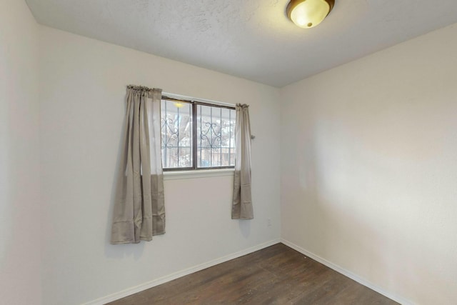 empty room featuring dark wood-type flooring and baseboards