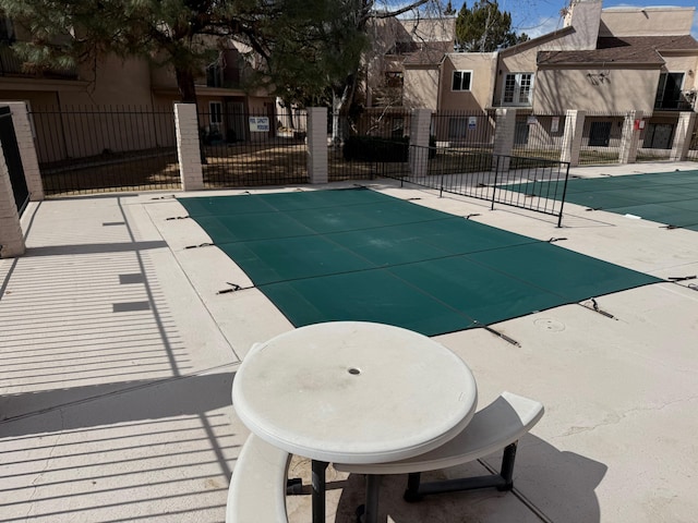 community pool featuring a patio area, fence, and a residential view