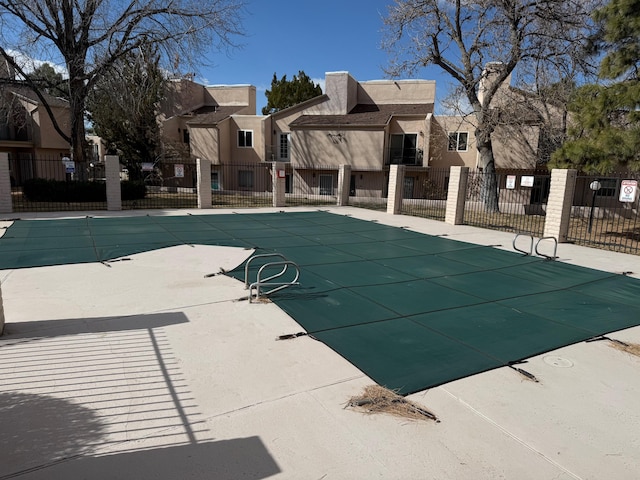 pool with a patio area, a residential view, and fence