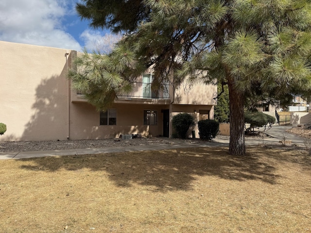 rear view of house featuring a balcony and stucco siding