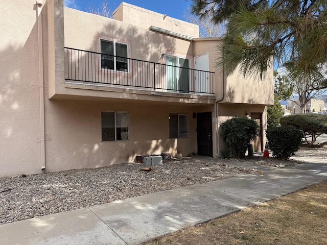 back of property featuring a balcony and stucco siding