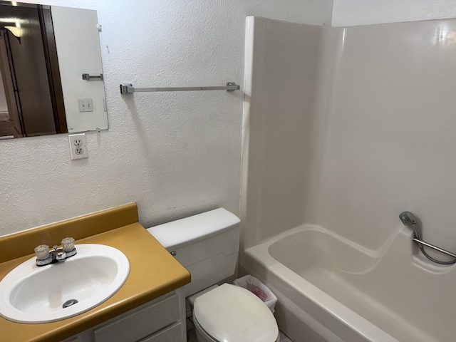 bathroom featuring a textured wall, vanity, and toilet