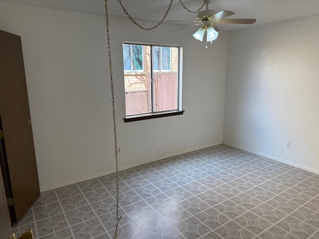 spare room featuring a ceiling fan, a textured ceiling, baseboards, and tile patterned floors