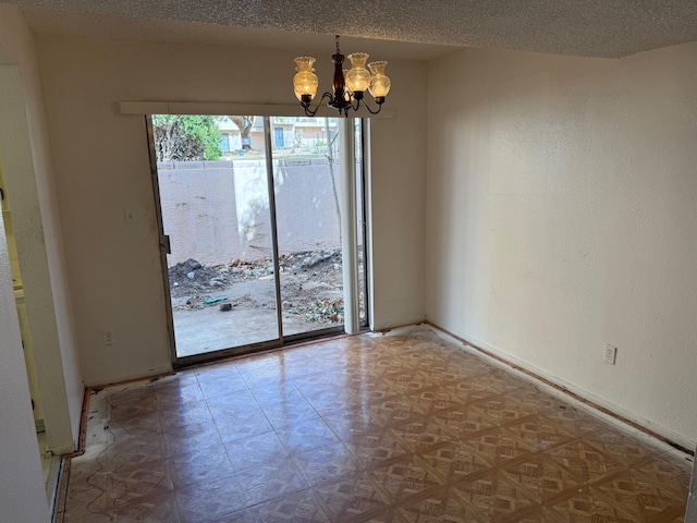 empty room with a notable chandelier, a textured wall, a textured ceiling, baseboards, and tile patterned floors