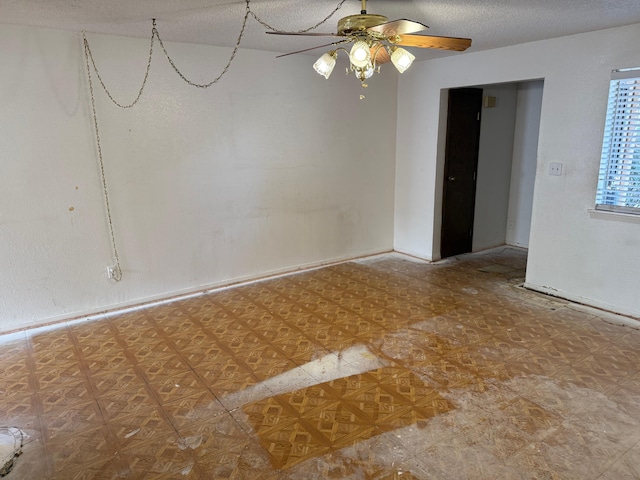 empty room with a textured ceiling, ceiling fan, and tile patterned floors