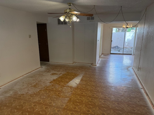 unfurnished dining area with visible vents, a textured ceiling, and ceiling fan with notable chandelier