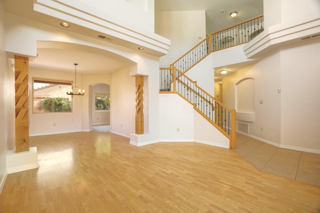 unfurnished living room with visible vents, stairway, and wood finished floors