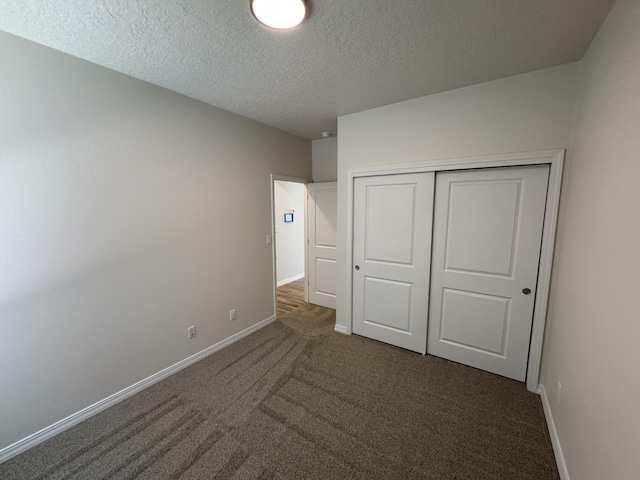 unfurnished bedroom with a textured ceiling, a closet, carpet, and baseboards