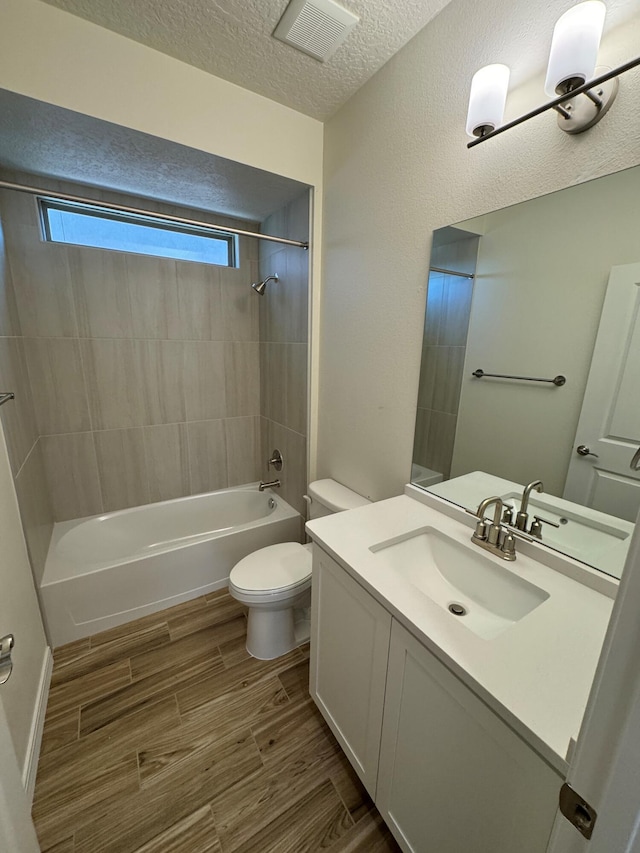 bathroom featuring shower / bath combination, toilet, visible vents, a textured ceiling, and wood finished floors