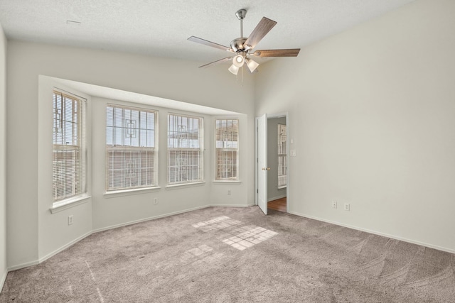 carpeted spare room with ceiling fan, baseboards, vaulted ceiling, and a textured ceiling