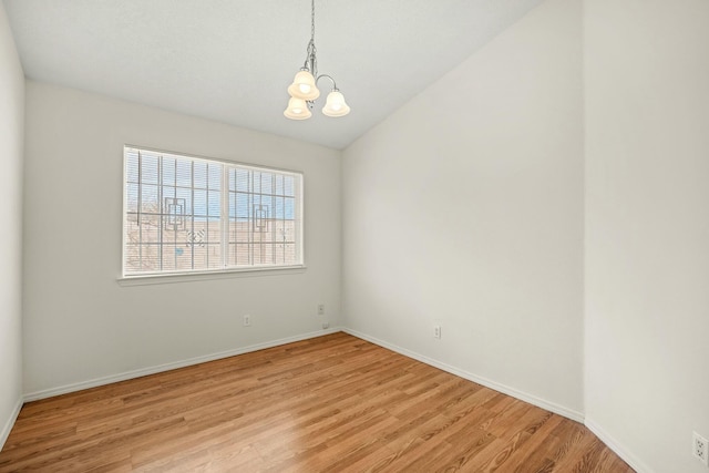 unfurnished room with light wood-style floors, lofted ceiling, baseboards, and an inviting chandelier