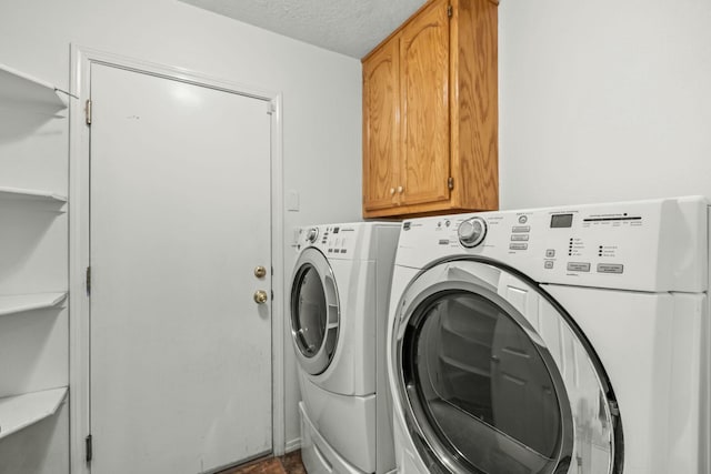 laundry room with cabinet space, independent washer and dryer, and a textured ceiling