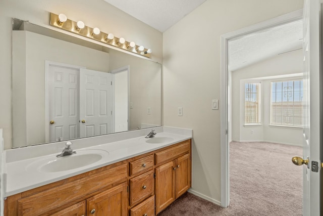 bathroom with lofted ceiling, double vanity, a textured ceiling, and a sink