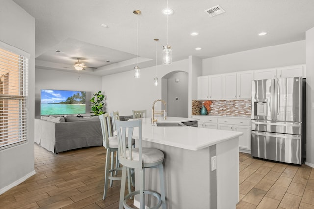 kitchen featuring arched walkways, a sink, wood tiled floor, stainless steel refrigerator with ice dispenser, and backsplash