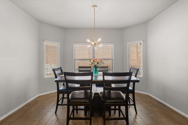 dining room featuring baseboards, a textured ceiling, an inviting chandelier, and wood finished floors