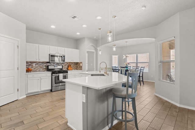 kitchen featuring stainless steel appliances, light countertops, visible vents, decorative backsplash, and wood tiled floor