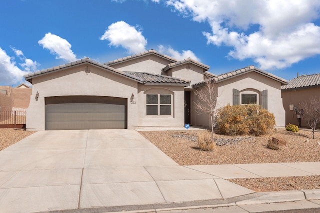 mediterranean / spanish house with a garage, concrete driveway, a tiled roof, and stucco siding