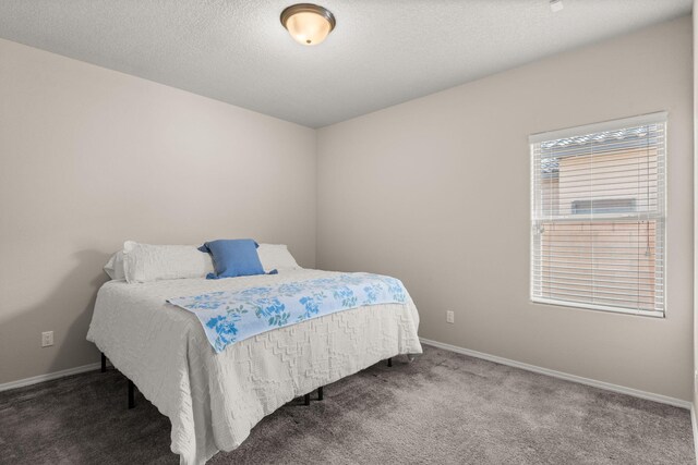 carpeted bedroom featuring baseboards and a textured ceiling