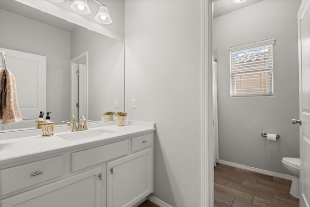 bathroom featuring toilet, wood finished floors, vanity, and baseboards