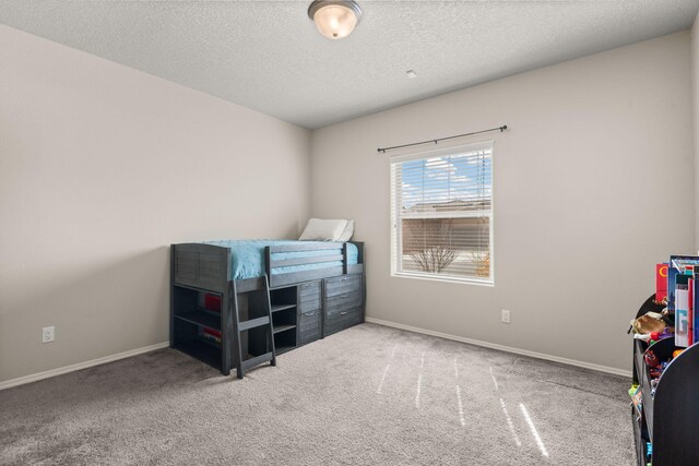 bedroom with carpet, baseboards, and a textured ceiling