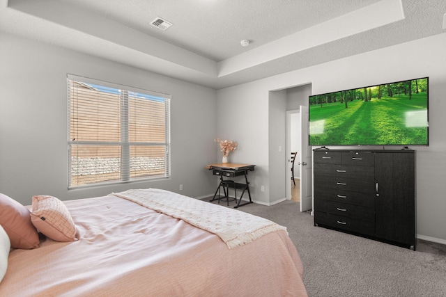 bedroom featuring light carpet, baseboards, visible vents, and a tray ceiling