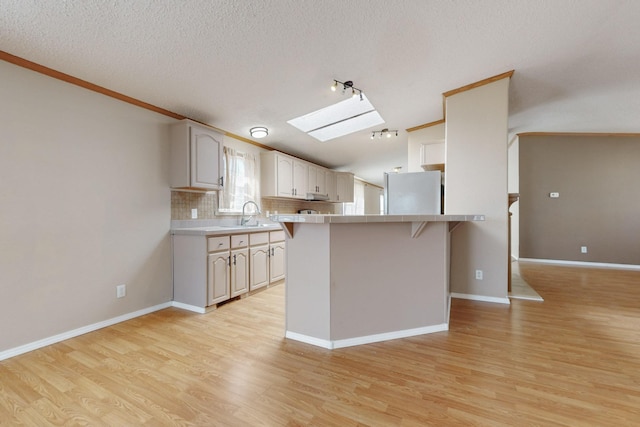 kitchen featuring tasteful backsplash, freestanding refrigerator, light countertops, and light wood-style flooring