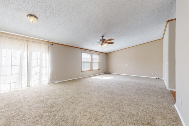 empty room featuring crown molding, visible vents, carpet flooring, ceiling fan, and baseboards