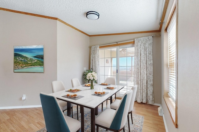 dining room with baseboards, light wood-style flooring, ornamental molding, and a textured ceiling