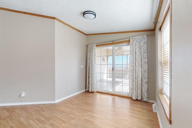 unfurnished room with a textured ceiling, ornamental molding, wood finished floors, and baseboards