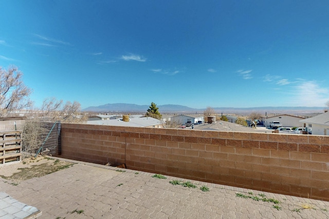 view of patio / terrace featuring a residential view, fence, and a mountain view