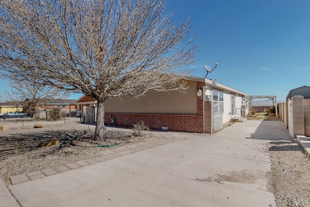 view of property exterior with brick siding and fence