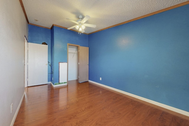 unfurnished bedroom featuring a textured ceiling, baseboards, crown molding, and wood finished floors