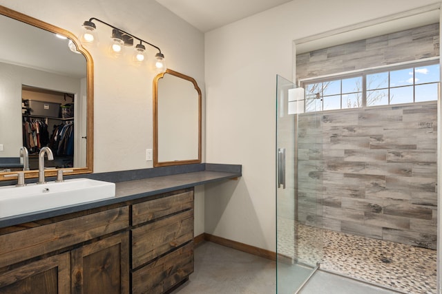 1800 Los Pinos Rd, Bosque Farms, NM 87068 - bathroom with tiled shower, vanity, a spacious closet, and baseboards