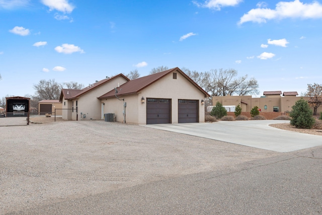 view of side of property featuring central air condition unit, stucco siding, an attached garage, fence, and driveway