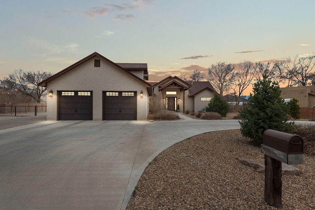 view of front of property featuring a garage, fence, concrete driveway, and stucco siding