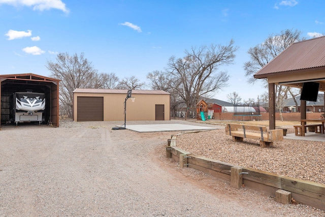 1800 Los Pinos Rd, Bosque Farms, NM 87068 - exterior space with a trampoline, a playground, a detached carport, and driveway