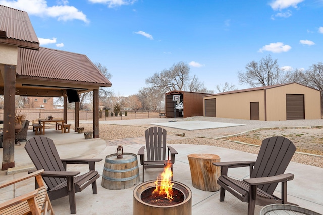 view of patio / terrace with fence, a fire pit, and an outdoor structure