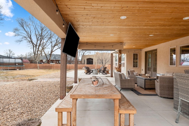 view of patio featuring outdoor dining space, a trampoline, fence, and an outdoor living space