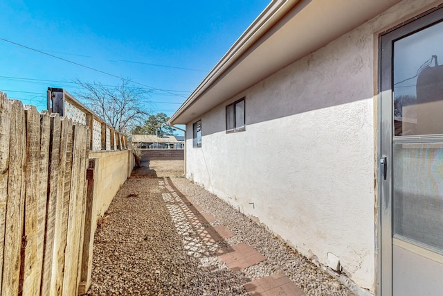 view of side of property featuring fence and stucco siding