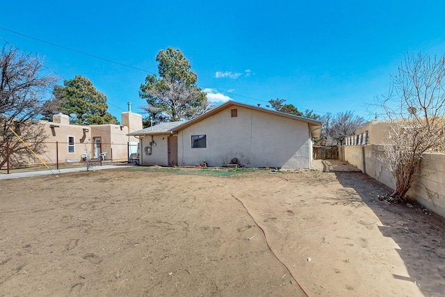 rear view of property featuring a fenced backyard and stucco siding