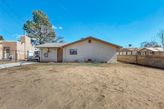 rear view of property with fence and stucco siding