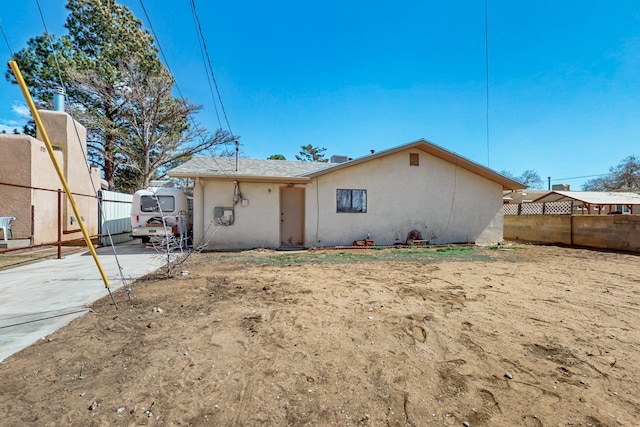 rear view of property featuring fence and stucco siding