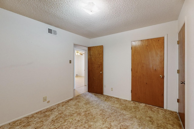 unfurnished bedroom with a textured ceiling, visible vents, and carpet flooring